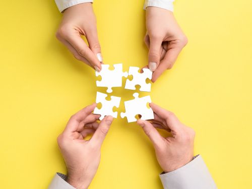 Piezas de rompecabezas unidas por dos manos